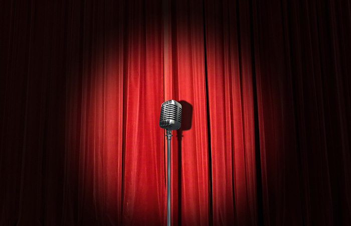 Image of a microphone on a stage. This article explains research around humour and humilitation