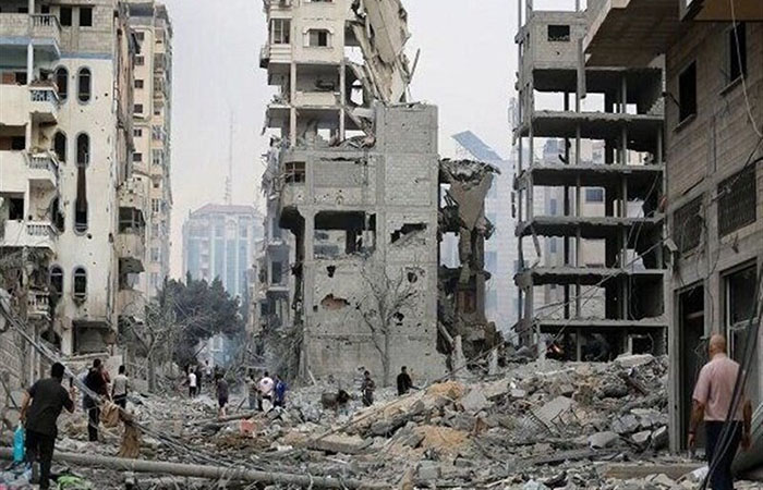 Destroyed buildings with people walking in rubble in the foreground, Gaza, Dec, 2023