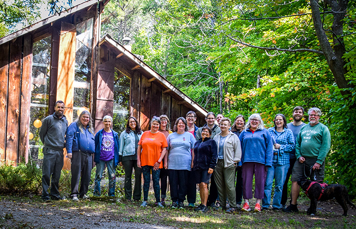 CFSC Members and staff stand outdoors in front of a wooden building