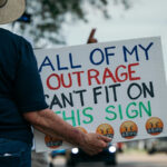 A protest sign reads: "All of my outrage can't fit on this sign."