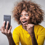 A woman looks excitedly at her phone